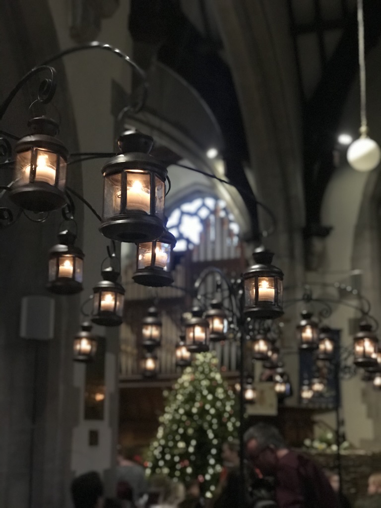 candles hung from stands in church with christmas tree in background